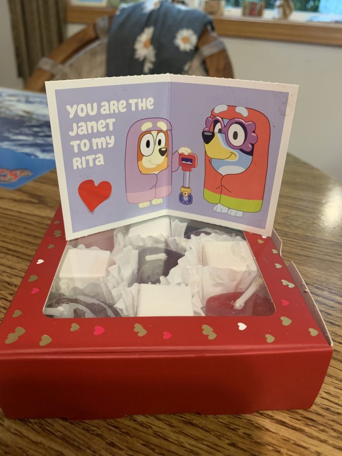 A paper Valentine showing the characters Bluey and Bingo from the show Bluey in granny outfits. The caption says "You are the Janet to my Rita"